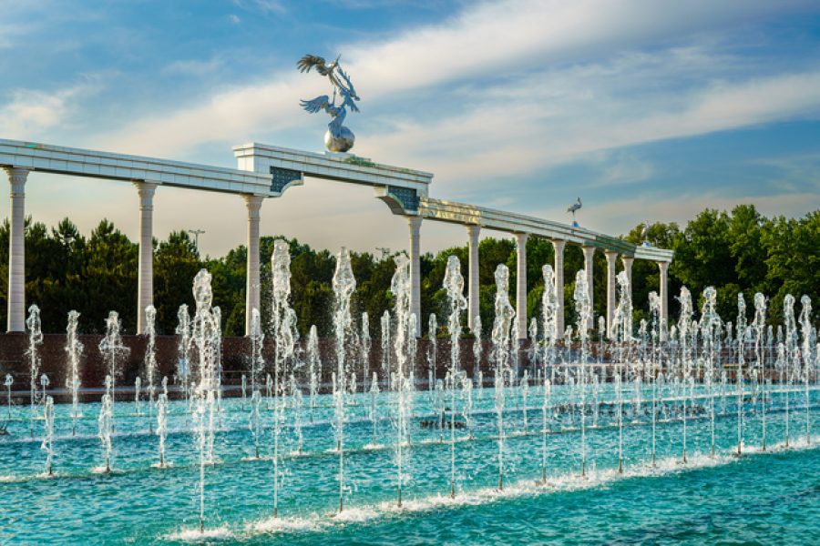 Memorial and rows of fountains illuminated by sunlight at sunset or sunrise in the Independence Square at summertime, Tashkent, Uzbekistan.